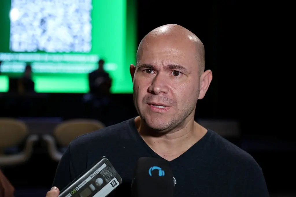 Foto horizontal colorida, em plano fechado, que mostra o prefeito de Cuiabá, Abilio Brunini, concedendo entrevista coletiva. Ele é um homem branco, careca, magro, usando camiseta cinza escura.