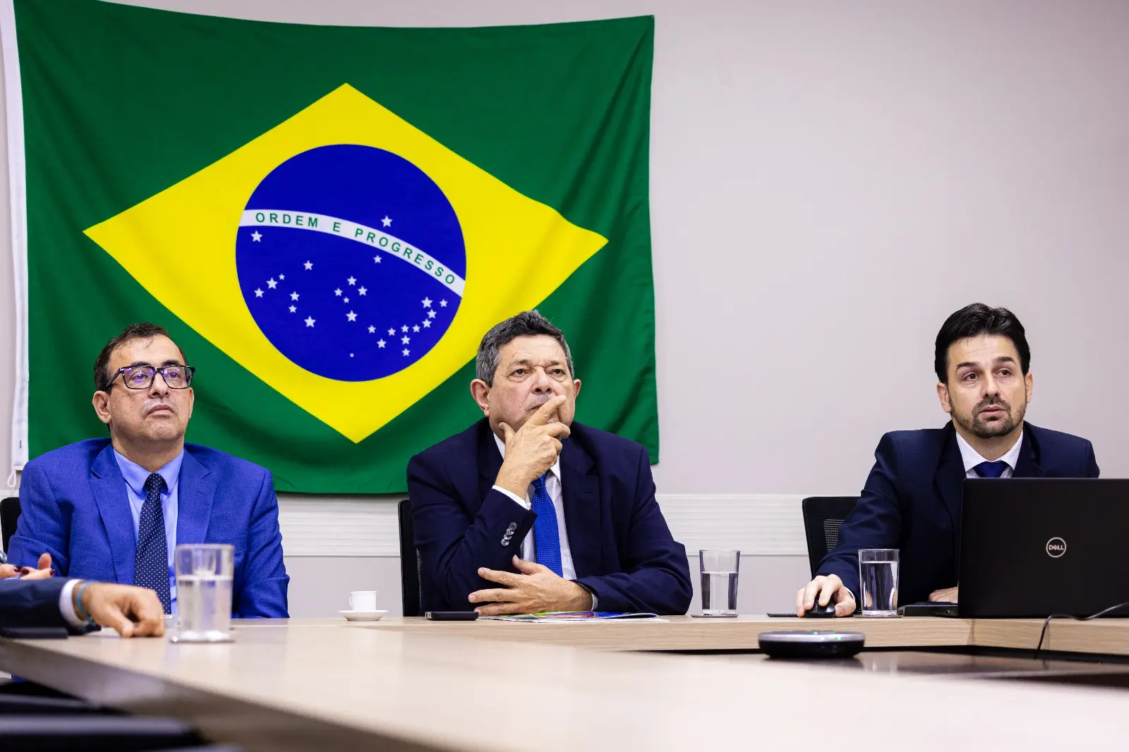 O diretor do Dapi, Guilherme Schultz, está sentado e utiliza um notebook para aapresentar o álbum digital aos participantes da reunião. À sua esquerda está o corregedor, desembargador José Luiz Leite Lindote e o juiz auxiliar, Jorge Alexandre Martins Ferreira.